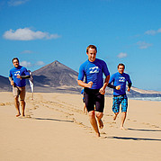 Calentamiento en la playa antes del curso de surf Empiezas tu curso de surf para principiantes en Fuerteventura con un ligero trote por la playa – la preparación perfecta para tu primera ola.