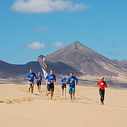 Alumnos del curso de surf se calientan trotando por la playa antes de entrar al agua.