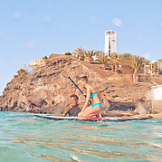 Un instructor de SUP surf te ayuda a subirte a la tabla