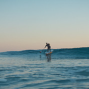 Remando una ola verde limpia sobre la tabla de SUP
